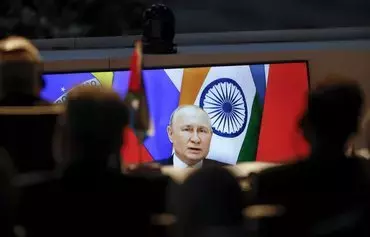 A screen shows Russian president Vladimir Putin virtually delivering remarks as delegates look on while attending a meeting during the 2023 BRICS Summit in Johannesburg on August 24. [Marco Longari /POOL/AFP]