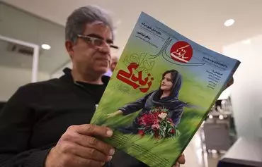 A man holds a copy of Iranian magazine Sazandegi reporting on the death of Mahsa Amini, a woman who died after being arrested by the Islamic Republic's 'morality police,' in Tehran on March 14. [Atta Kenare/AFP]