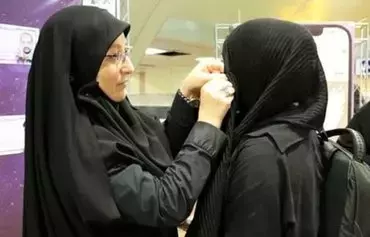 در این عکس بدون تاریخ، یکی از مأموران رژیم در تهران مقررات پوشش اجباری موی سر را اجرا می‌کند. این مأموران تا روز ۲۵ شهریور ۱۴۰۱، زنانی را که به رعایت «پوشش اجباری موی سر مورد تأیید حکومت» پایبند نبودند، کنار می‌کشیدند، روسری‌شان را درست می‌کردند، یا به آنها یک روسری می‌دادند تا بر سر بگذارند. [فارس]