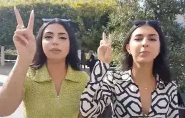 This screenshot from a video shows two girls chanting 'Let's start a revolution; with or without headscarves!' [Social media]