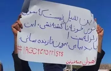 A protester in Zahedan on September 29 holds a sign saying, 'This is not a flood, it's a quake, leave your homes [and protest] to stay alive. #IRGCTerrorists #ZahedanBloodyFriday.' [Social media]