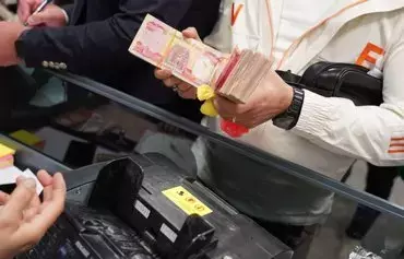 An Iraqi holds a bundle of Iraqi dinars to buy US dollars at one of the sales outlets opened by banks to facilitate Iraqis' access to hard currency, on February 9. [Iraqi Rafidain Bank]