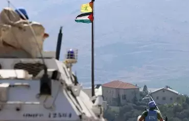 The Palestinian flag and the flag of Hizbullah wave in the wind as peacekeepers from the United Nations Interim Force in Lebanon patrol the border area between Lebanon and Israel on Hamames hill in the Khiyam area of southern Lebanon, on October 13. [Joseph Eid/AFP]