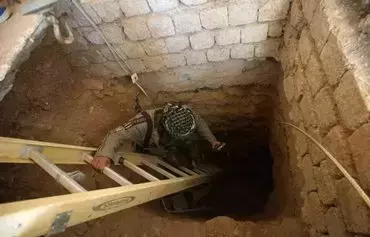 An Iraqi militia member looks down an underground tunnel previously used by ISIS near Tal Afar, Iraq. Iran-backed militias have been using ISIS tunnels to smuggle arms into Syria from Iraq. [Ahmad al-Rubaye/AFP]