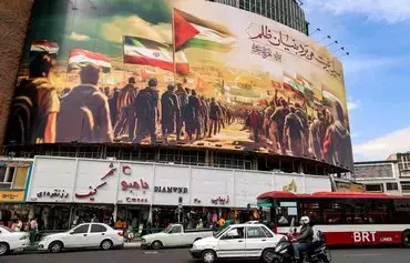 Motorists October 25 drive past a giant billboard depicting Muslim peoples walking with their national flags towards the Dome of the Rock shrine in Jerusalem, erected in Valiasr Square in the center of Tehran. [Atta Kenare/AFP]