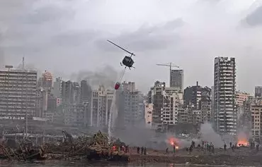 A helicopter tries to put out multiple fires at the scene of the massive explosion that hit Beirut's port on August 4, 2020, in the heart of the Lebanese capital. Some Lebanese blame Hizbullah for the explosion for storing explosive materials in the port silos. [AFP]