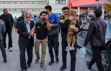 People injured in twin bombings that struck a crowd marking the anniversary of the 2020 killing of IRGC commander Qassem Soleimani are helped outside a hospital in the southern Iranian city of Kerman on January 3. [Sare Tajalli/ISNA/AFP]