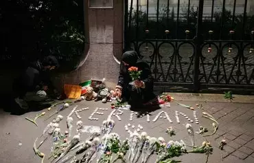 یک زن روز ۱۴ دی در مراسم یادبود قربانیان دو بمب‌گذاری که یک روز قبل از آن در کرمان روی داد، گل در دست دارد. در این انفجارها که داعش مسئولیت آن را بر عهده گرفت، دست‌کم ۸۴ تن کشته و صدها تن زخمی شدند. [دیمیتر دیلکوف/ خبرگزاری فرانسه]