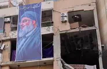 A photograph taken January 8 shows a banner depicting Hizbullah chief Hassan Nasrallah on a building hit by a drone attack that killed a Hamas leader in Beirut's southern suburb on January 2. Hizbullah operates a joint operations room with other Iranian proxies in Beirut. [Anwar Amro/AFP]