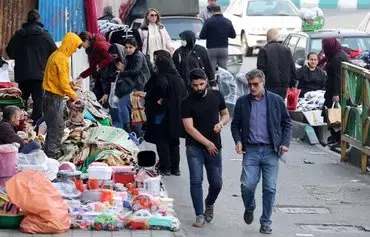 روز ۱۳ اسفند، مردم در کنار خیابانی در تهران راه می‌روند. [عطا کناره/خبرگزاری فرانسه]