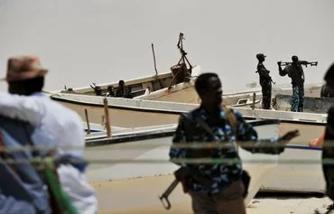 Armed militiamen and pirates stand among fishing boats in the central Somali town of Hobyo in 2010. [ROBERTO SCHMIDT/AFP]