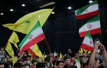 People wave Iranian and Hizbullah flags during a rally to mourn the death of Iranian President Ebrahim Raisi, in Beirut's southern suburbs on May 24. [Anwar Amro/AFP]