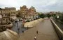 
People wade in the water on a flooded street following heavy rainfall in the old city of Sanaa on August 1, 2022. [Mohammed Huwais/AFP]        