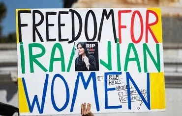 Protesters hold a placard during a September 15 march in Paris on the second anniversary of the death, in 'morality police' custody in Iran, of Mahsa Amini. [Sameer al-Doumy/AFP]