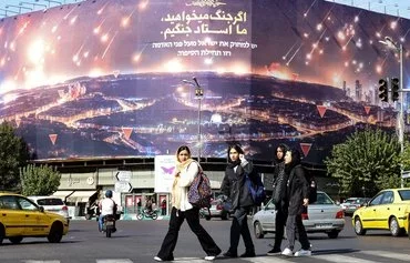 روز ۵ آبان، زنان از کنار یک بیلبورد ضداسرائیل در تهران رد می‌شوند. [عطا کناره/خبرگزاری فرانسه]