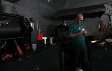 A man prepares an order using his phone light in the kitchen of a Tehran cafe during a November 12 electricity outage. [Atta Kenare/AFP]