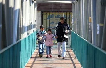 A woman and her children cross a pedestrian bridge in Tehran on December 4. [Atta Kenare/AFP]