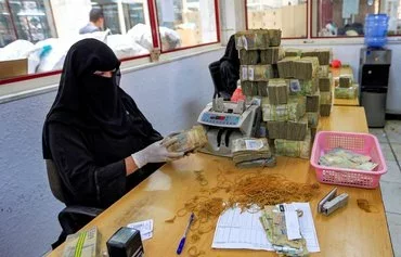 An employee counts currency at the central bank in Houthi-controlled Sanaa, June 23, 2021. [Mohammed Huwais/AFP]